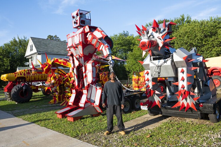 红色和黄色的怪物卡车和银色的机器人耸立在汽车创新者蒂姆·威利斯的土地上。