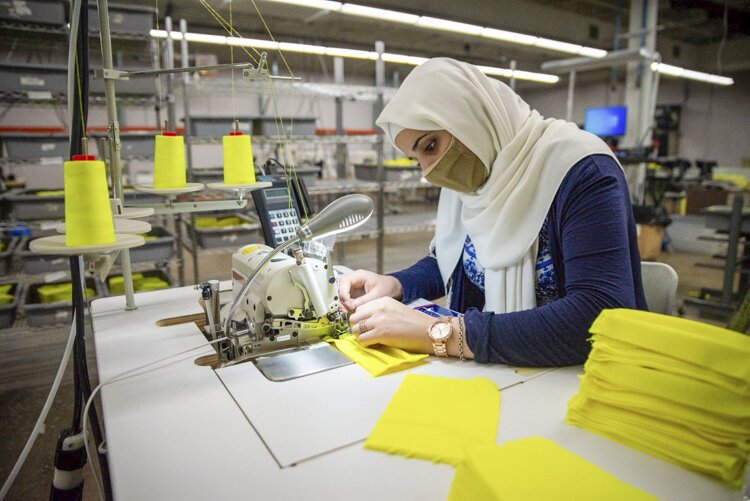 Nadia Akhlif在National Safety Apparel缝制一个口罩，这是该公司生产口罩和防护服以对抗冠状病毒的一部分。