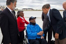 坐在轮椅上的老斯坦利·托利弗与巴拉克·奥巴马总统握手。左边是克利夫兰市长弗兰克·杰克逊，右边是副总统乔·拜登。